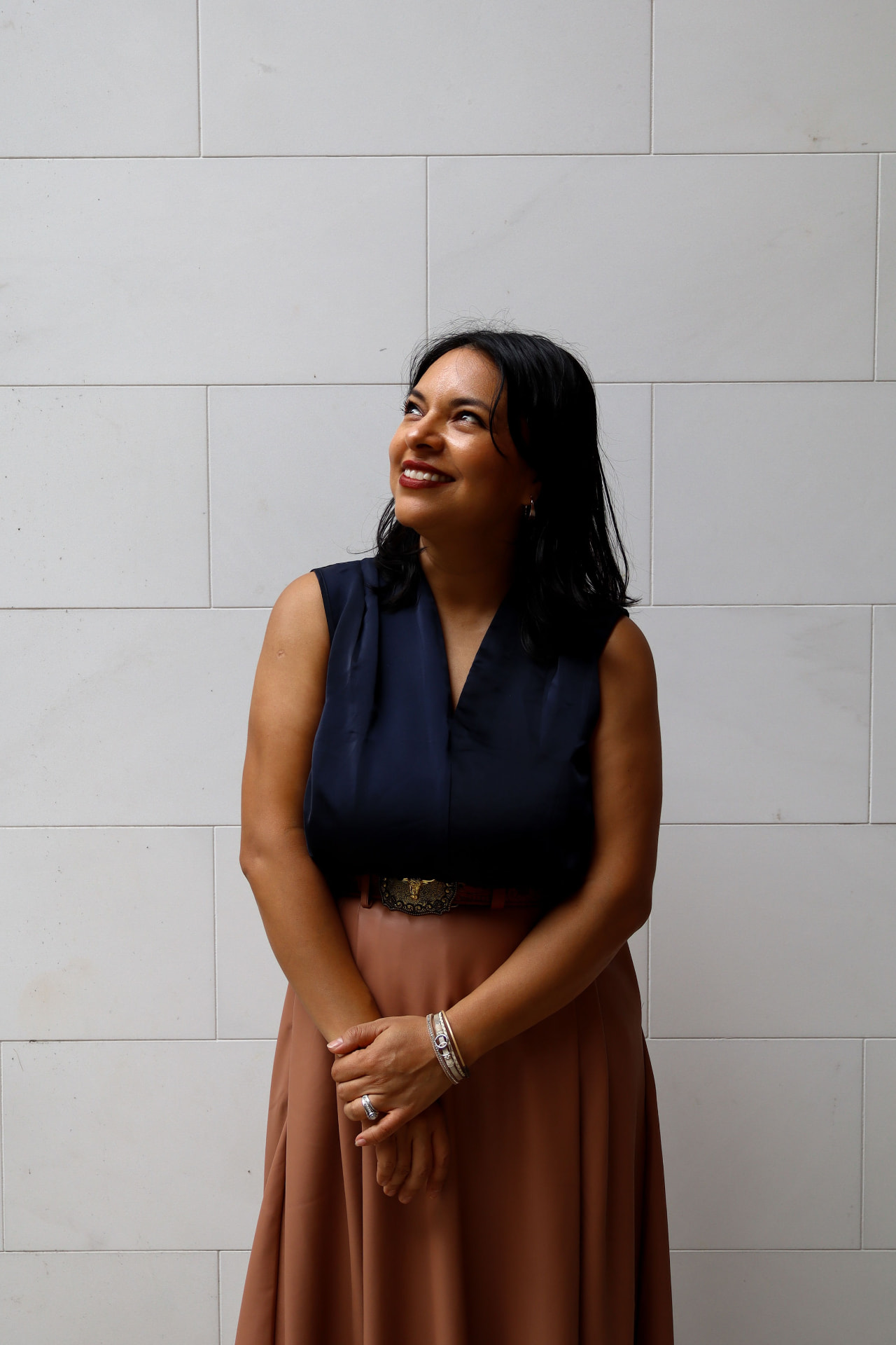 Nay Reyes, founder and principal designer of PATHIO Studio, against a light architectural stone wall